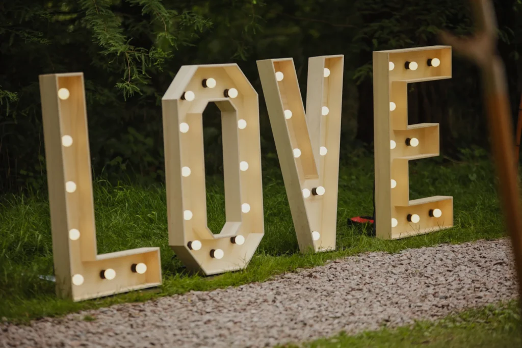 Grote verlichte houten LOVE-letters met lampjes in een groene tuin als decoratie voor bruiloften en evenementen.
